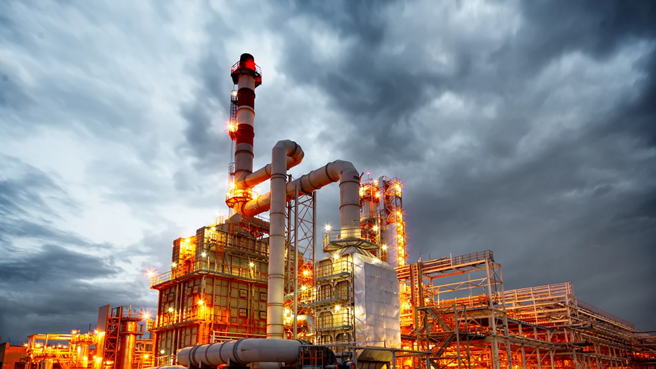 Lit-up oil refinery with cloudy skies.