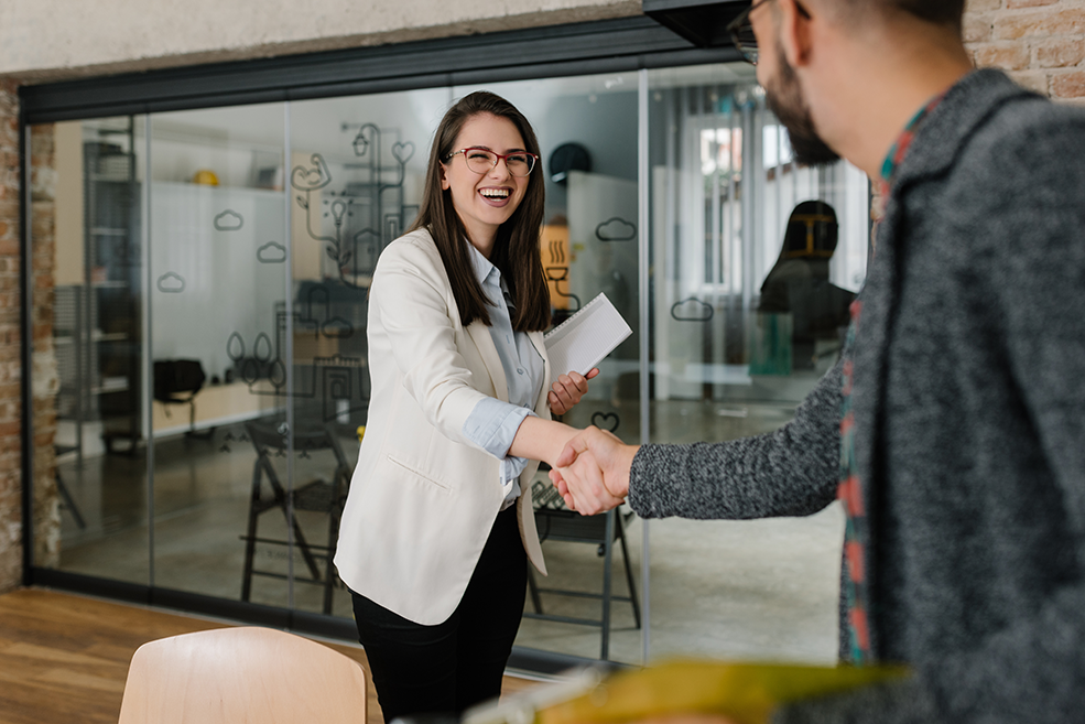 Quality candidate smiling and shaking hands with the human resource manager.