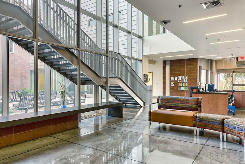 Stairwell going up to second floor, with windows showing seating in the courtyard outside.